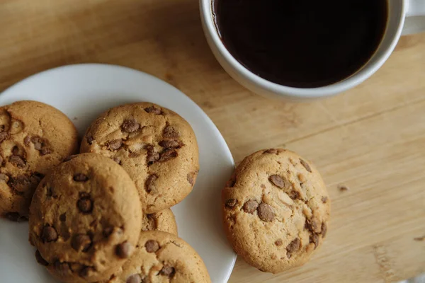 Brown cookies on the white plate and coffee in white glass — Stock Photo, Image