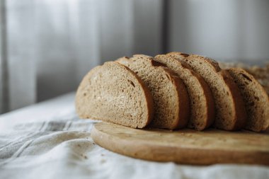 Beyaz bir masa örtüsünün üzerinde dilimlenmiş ekmek.