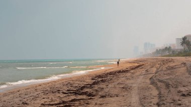 Geniş kumsalda yürüyen yalnız adam. uzakta