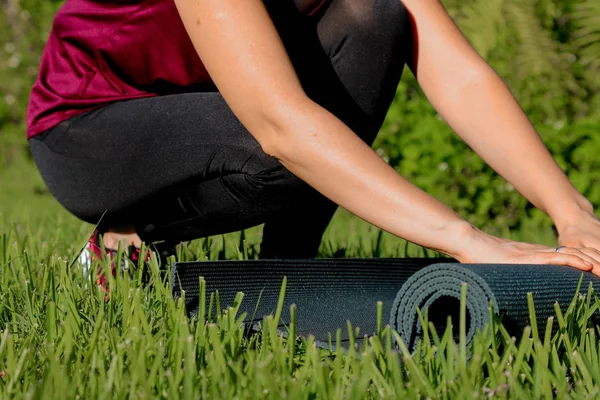Close up Hand and Yoga mat on green grass ready for practice and relax with yoga outdoor,Recreation Concept