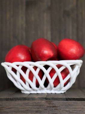 Ev bahçesinden büyük kırmızı elma beyaz bir arka plan üzerinde bir vazo beyaz hasır seramik yalan