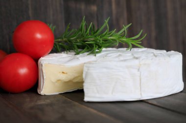 Whole Brie cheese  in the background red tomatoes and wooden background