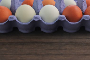 Ahşap arka plan üzerinde izole mavi karton kutu kahverengi tavuk yumurtası.