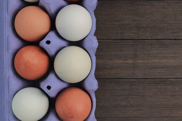 Brown chicken eggs in a blue carton box isolated on wooden background.