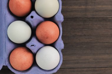 Ahşap arka plan üzerinde izole mavi karton kutu kahverengi tavuk yumurtası.