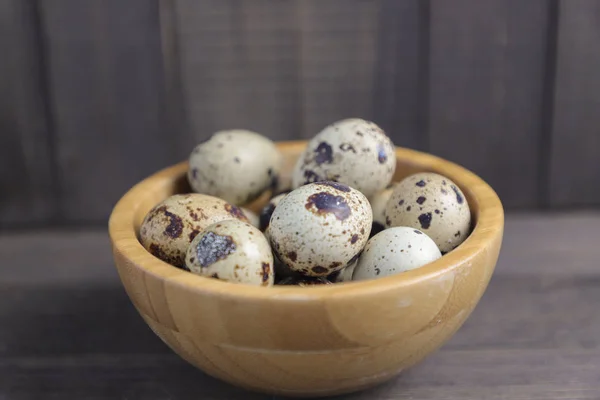 Křepelčí vejce v dřevěné míse na hnědém pozadí — Stock fotografie
