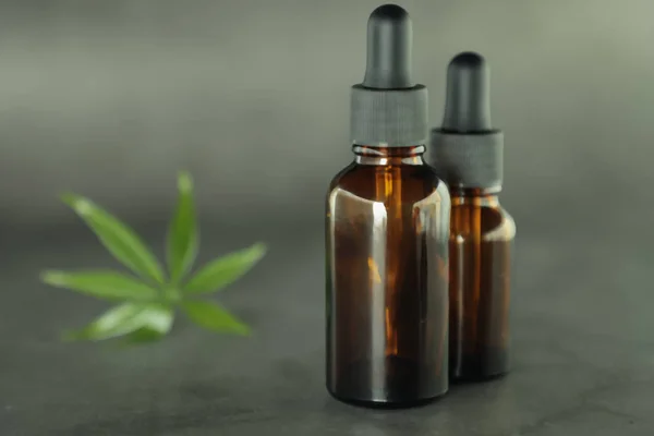 Tam ile koyu cam şişeler, cannabidiol yağı ve kenevir bir pastel arka plan üzerinde yaprakları. Sağlık anlayışı. Tıbbi marihuana.