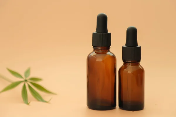 Tam ile koyu cam şişeler, cannabidiol yağı ve kenevir bir pastel arka plan üzerinde yaprakları. Sağlık anlayışı. Tıbbi marihuana.