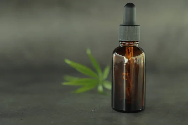 Tam ile koyu cam şişeler, kannabidiol yağı ve kenevir koyu bir arka plan üzerinde yaprakları. Sağlık anlayışı. Tıbbi marihuana.