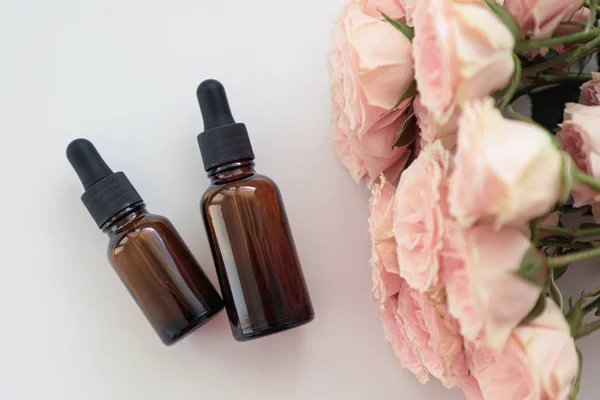 Koyu kozmetik şişeler, üzerinde pembe güller var. Kopya alanı. Dostu doğal kozmetik konsepti. Minimalizm. Güzellik blogger, spa salonu, terapy salon.