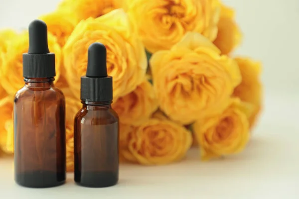 Koyu kozmetik şişeler, parlak bir arka plan üzerinde sarı güller ile. Kopya alanı. Dostu doğal kozmetik konsepti. Minimalizm. Güzellik blogger, spa salonu, terapy salon.