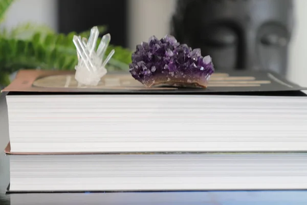 Closeup of pile of books with purple  amethyst and clear quartz