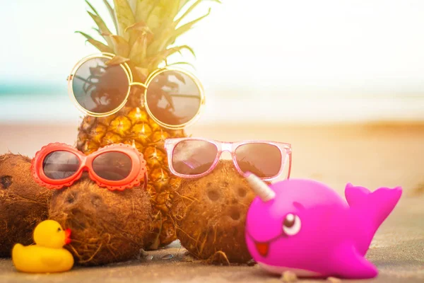 Çok güzel ananas ve hindistancevizi güneşli tropikal kumsalda güneş gözlüğü takıyor