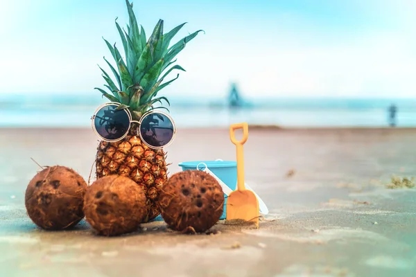 Güneş gözlüğü ve hindistancevizi rahatlatıcı güneşli kumsalda giyen sevimli ananas