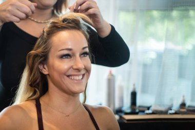 Genç güzel gülümseyen kadın saç Getting kıvrılmış