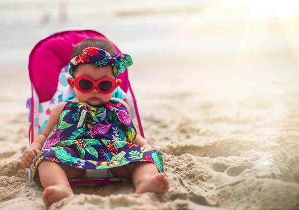 Güneş gözlüğü ve Karayipler sahilde oturmuş kafa bandı giyen güzel bebek kız