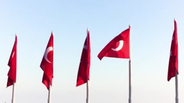Türk bayrağı açık gökyüzüne karşı rüzgarda dalgalanıyor, bayrak bir yıldız ve ay ile kırmızı.