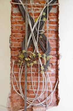 Bir tuğla duvar zemin üzerine karışık elektrik borular.