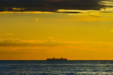 Konteyner liman Gdansk, günbatımında yaklaşan gemi silueti ile deniz manzarası. Gdansk Bay, Pomerania, Kuzey Polonya.
