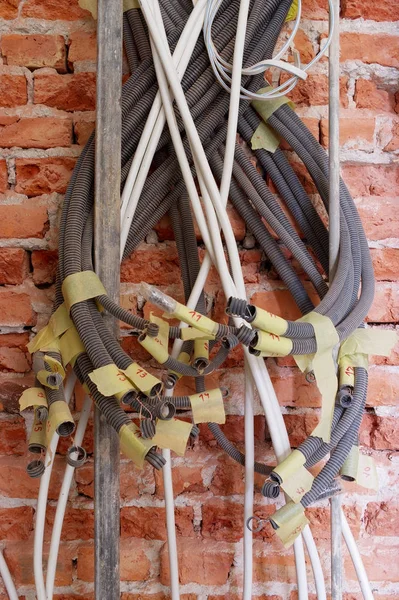 Bir tuğla duvar zemin üzerine karışık elektrik hatlarından yakın çekim.