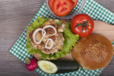 Lezzetli ev yapımı tavuk burger taze marul, domates, salatalık ve turp ahşap zemin hazırlanıyor. Metniniz için boş bir alanı ile. Yukarıdan görüntüleyin. Fast food-öğle.