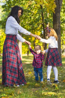 Güzel genç anne parkta çocuklarını sonbaharda çalış. Onlar birlikte geçirmek ve güneşli, güzel bir sonbahar gün içinde parkta iyi eğlenceler iyi eğlenceler