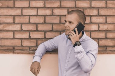 Yakışıklı genç bir eski bina önünde duruyor ve bir cep telefonu üzerinde görüşmeler. 