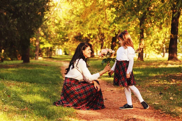 年轻的母亲和女儿在一个美丽的秋天白天一起在户外享受 他们很高兴 一个小女孩想给她母亲一束美丽的花朵 — 图库照片