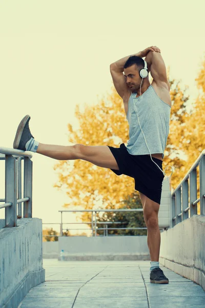 Stretching out.Young male jogger athlete training and doing workout outdoors in city