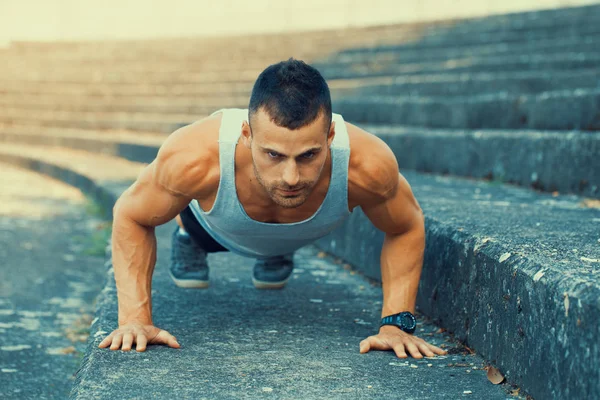 Portrait of a fitness man doing push ups outdoors