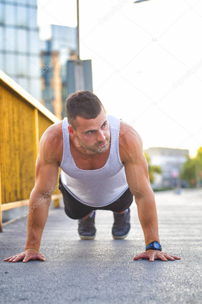 Young sportsman doing push ups outdoors, fitness and exercising on the bridge. Sport and lifestyle concept