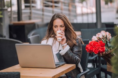 Arkadaş grubu manifatura tarama web ve sosyal ağ besleme, Sokak kafede oturan ve kahve içme dizüstü bilgisayar ile gülümseyen kadın 