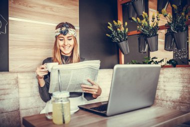 Gazete okuma ve sabah kafede dizüstü bilgisayar kullanırken kahve içme güzel mutlu genç kadın. Blogger iş kavramı