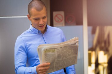 Arka bina ile gazete okurken yakışıklı bir genç adam portresi kapatın