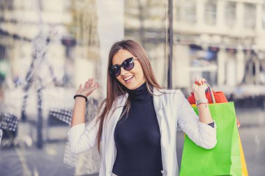 Alışveriş torbaları tutarak ve vitrin duran güzel genç moda kadın