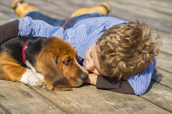 Küçük şirin çocuk nehir kenarında köpeğiyle oturuyor. Birlikte güzel güneşli bir günde hoşlarına gidiyor. Çocuk onun köpek yavrusu sarılma. Ben büyürken, hayvanlar - köpek, boş zaman, seyahat, tatil için seviyorum. Kopya alanı