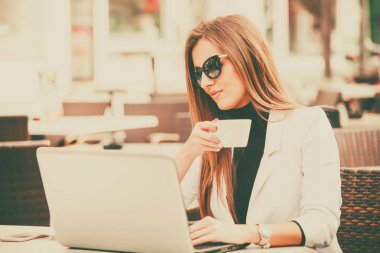 Mutlu girişimci ile bir dizüstü bilgisayar ve sokağın ortasında bir caffee dükkanda kahve içme