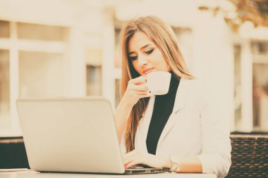 Mutlu girişimci ile bir dizüstü bilgisayar ve bir sokak kafede kahve içme