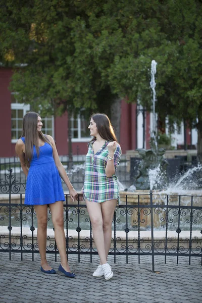 两个女孩在公园前面的喷泉 选择性对焦和小景深 镜头耀斑 — 图库照片