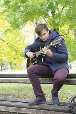 Genç adam bir akustik gitar, seçici odak ve küçük derinlik-in tarla, lens flare
