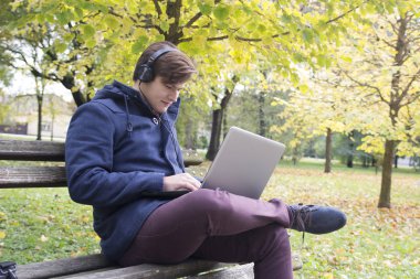 Park, seçici odak ve küçük derinlik-in tarla, içinde laptop ile genç adam lens flare