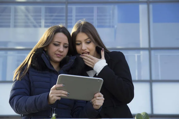 Two young business women with a tablet in hand