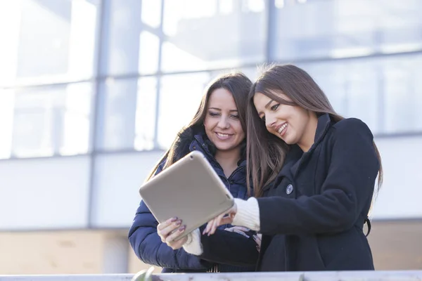 Two young business women with a tablet in hand