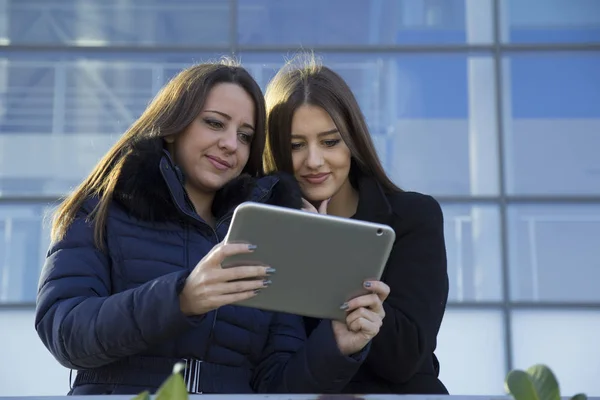 Two young business women with a tablet in hand