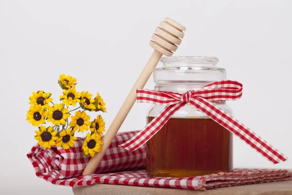 Honey in  jar with honey dipper on a wooden background