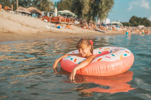 炎热的夏天 快乐的小女孩在水中玩充气戒指 孩子们学习游泳 儿童水玩具 — 图库照片