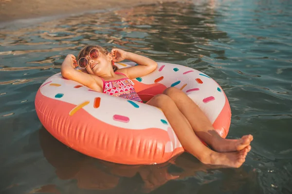 夏の暑い日に水で膨らませてリングで横になっている幸せな女の子 子供たちは泳げるようになります 子水のおもちゃ — ストック写真