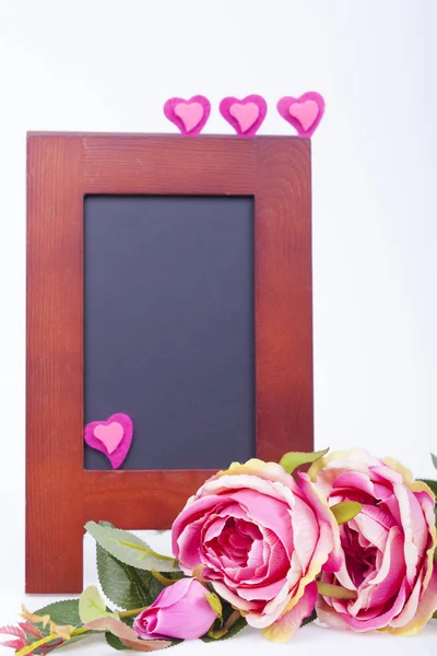 Pink rose, pink  hearts and writing board on a white background