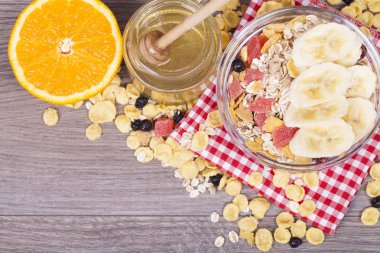 Kavanoz ve ahşap arka plan üzerinde şekerlenmiş meyve mısır gevreği, müsli, portakal, rendelenmiş muz, tatlım. Metniniz için boş alan ile. Üstten görünüm.