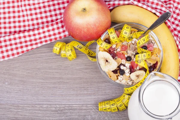 Fitness concept with yoghurt, muesli and fruit on a wooden background